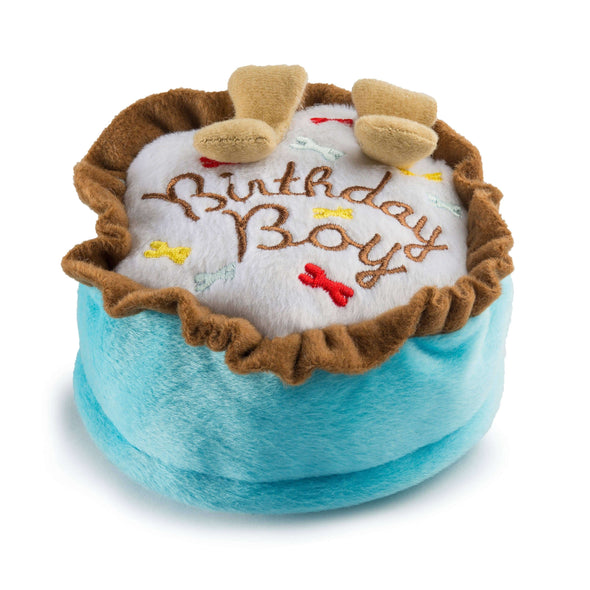 Stuffed dog toy in the shape of a birthday cake. The toy has Birthday Boy written on top of it.